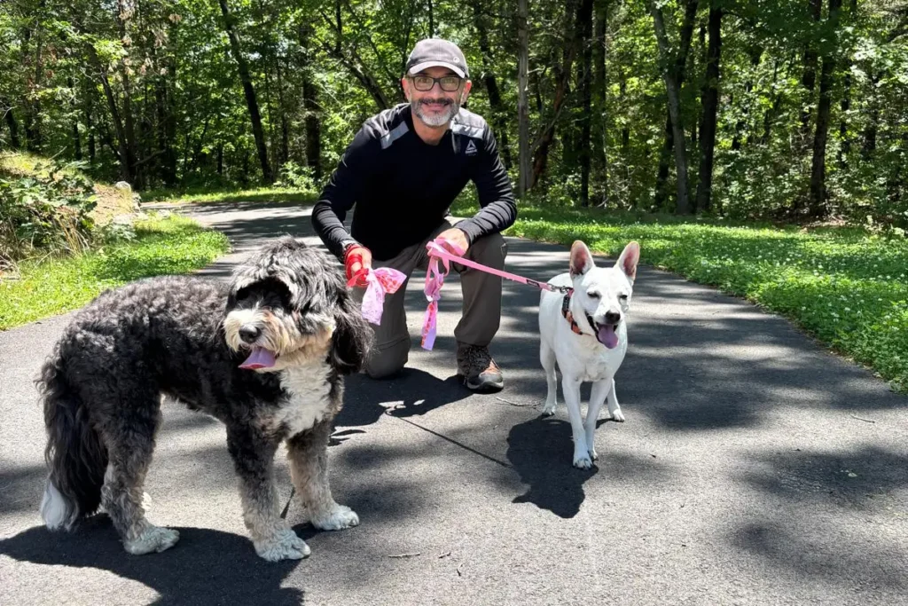 House sitting como funciona: Mauricio y Adriana paseando a los perros durante una experiencia de housesitting en un barrio residencial.